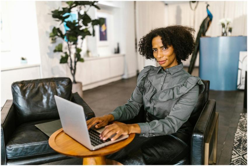 Confident businesswoman with afro hair typing on l