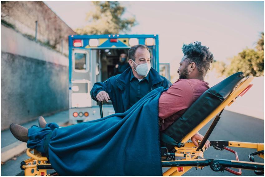 A paramedic aids a man on a stretcher near an ambu