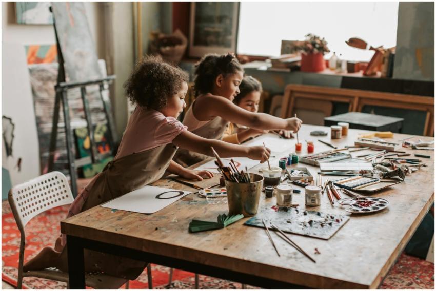 Three young girls engaged in painting at an indoor