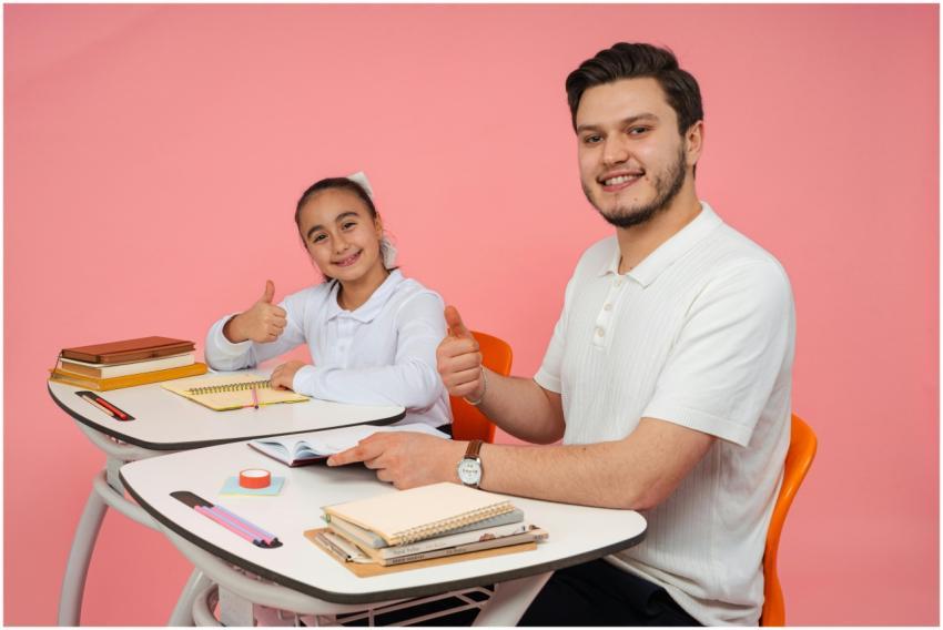 Smiling teacher and student at a desk, thumbs up,