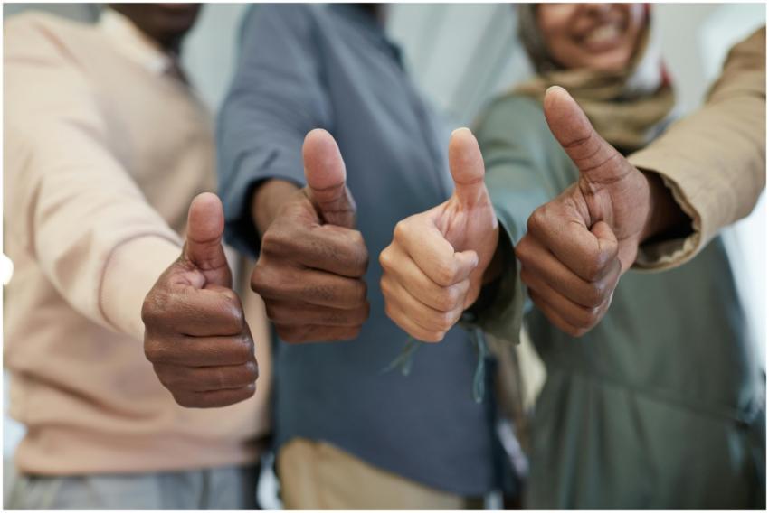 Close-up of a diverse team giving thumbs up indoor