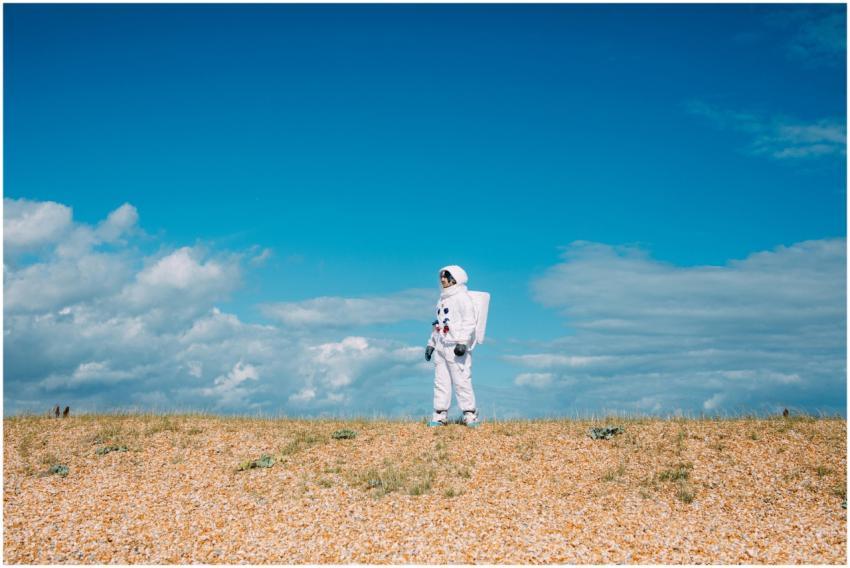 An astronaut in a spacesuit stands alone in a dese