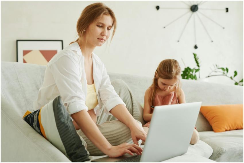 A mother and daughter use a laptop together on a c