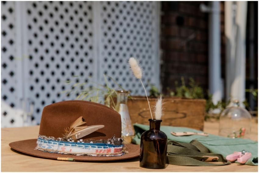 A rustic brown hat with feathers on a table with b