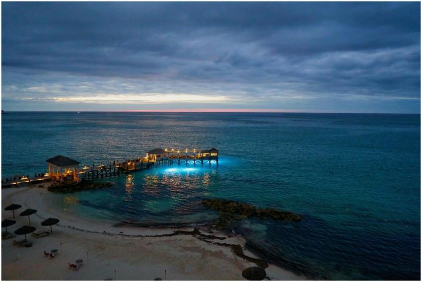 A tranquil seascape at twilight with a pier illumi