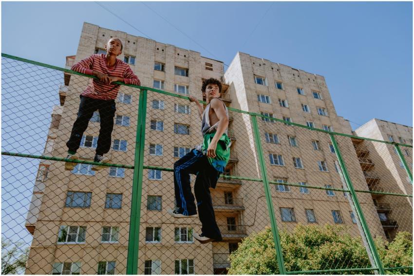 Teen boys climbing a metal fence near a residentia