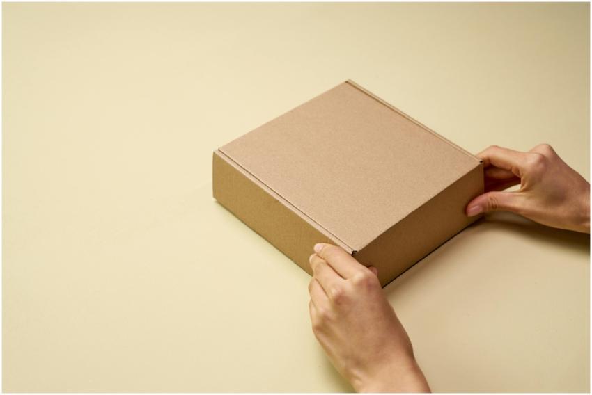 A close-up of hands opening a plain brown cardboar