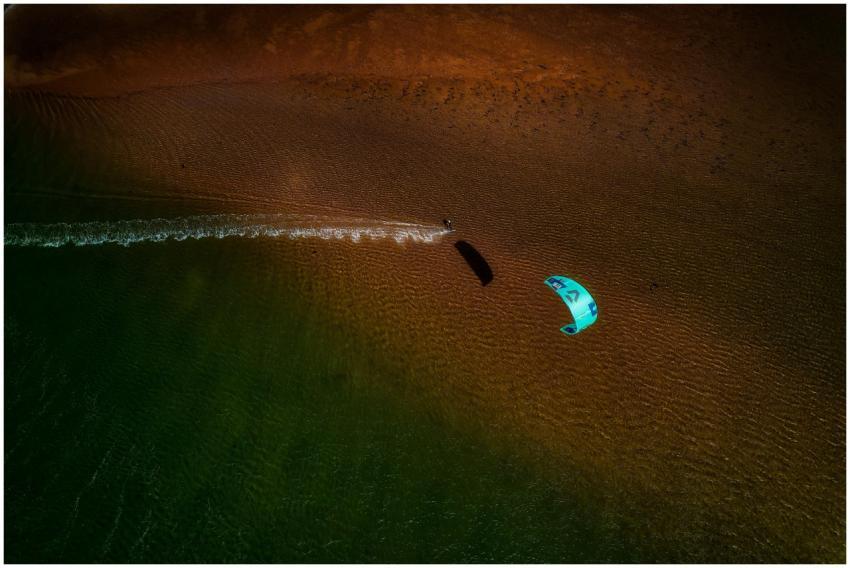 Dynamic aerial shot of kite surfer gliding over th