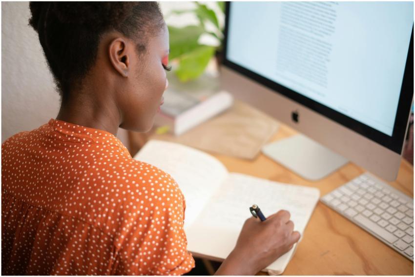 A woman in a polka-dot shirt writes in a notebook