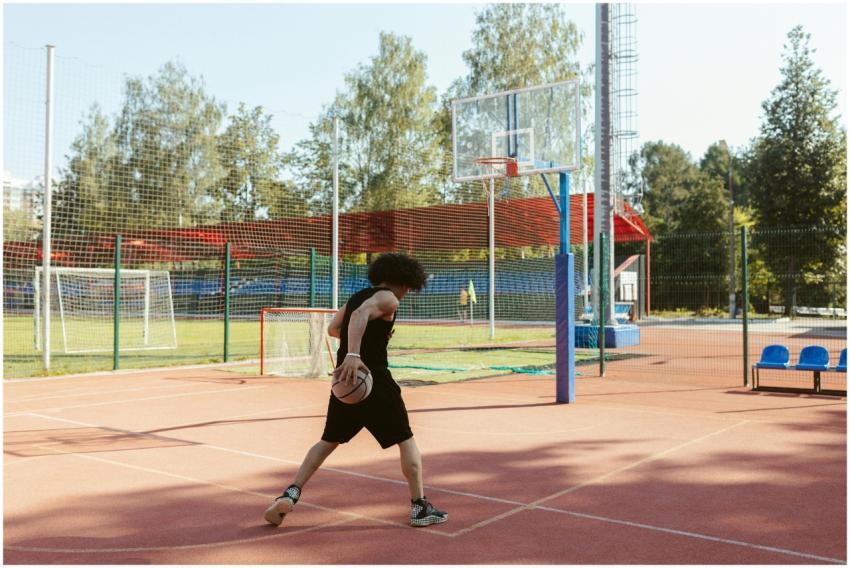 A young man dribbles a basketball on an outdoor co