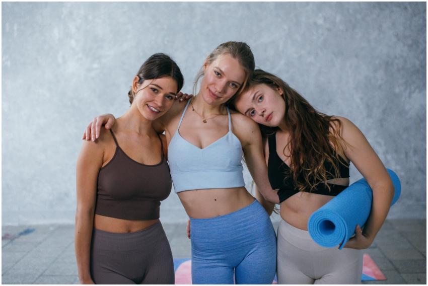 Three women in activewear posing together with yog