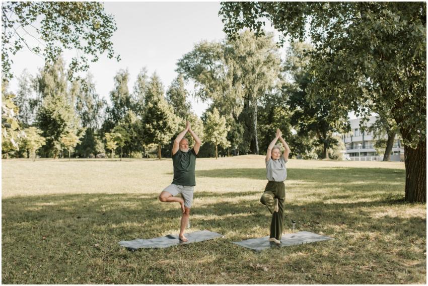 Elderly couple performing yoga in a sunny park, en