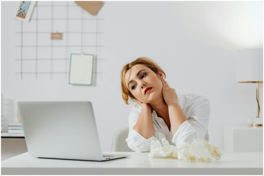 Tired woman sitting at desk with a laptop, appeari