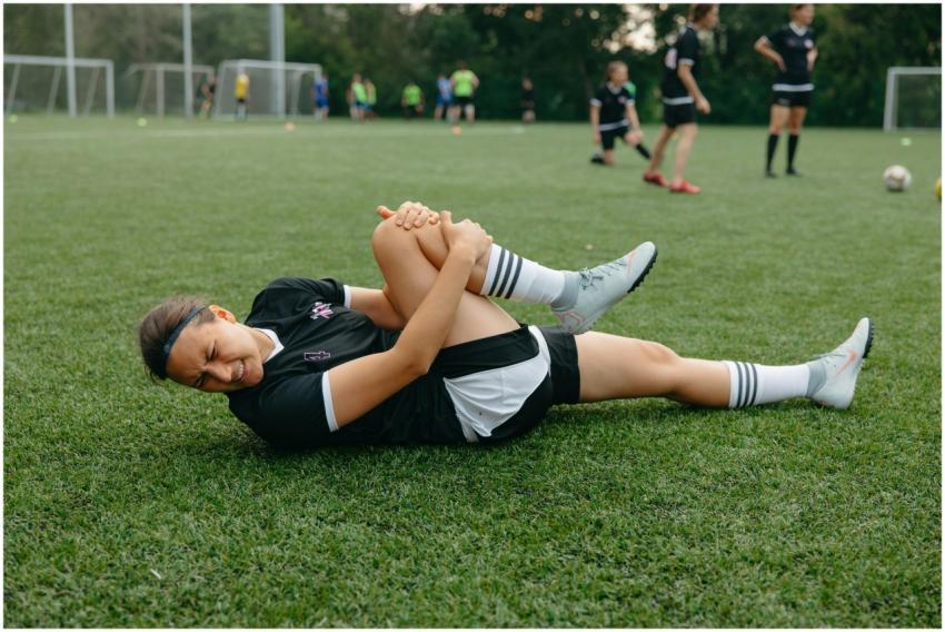 A female soccer player lying on the field, holding