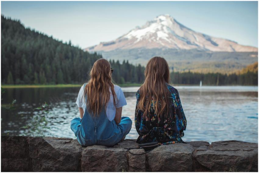 Two women sitting by a lake with a stunning view o