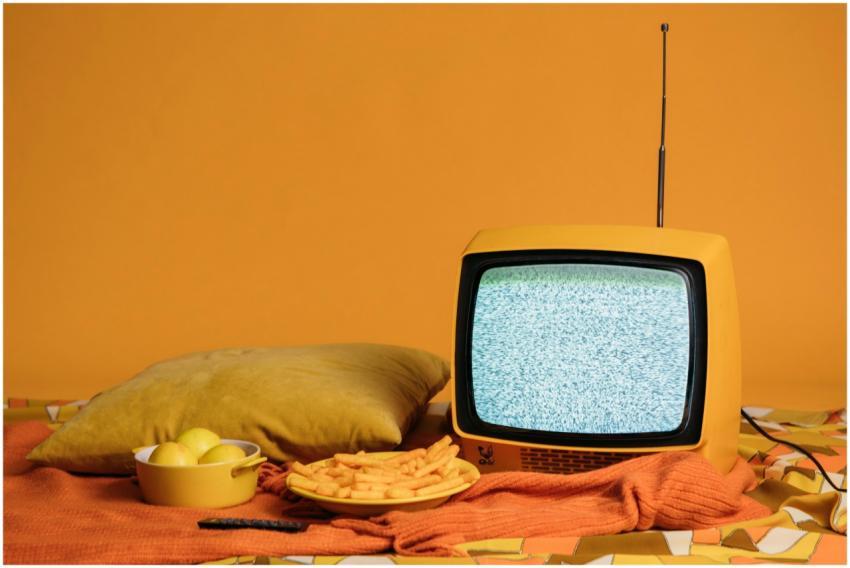 A vintage yellow TV with static, surrounded by fri