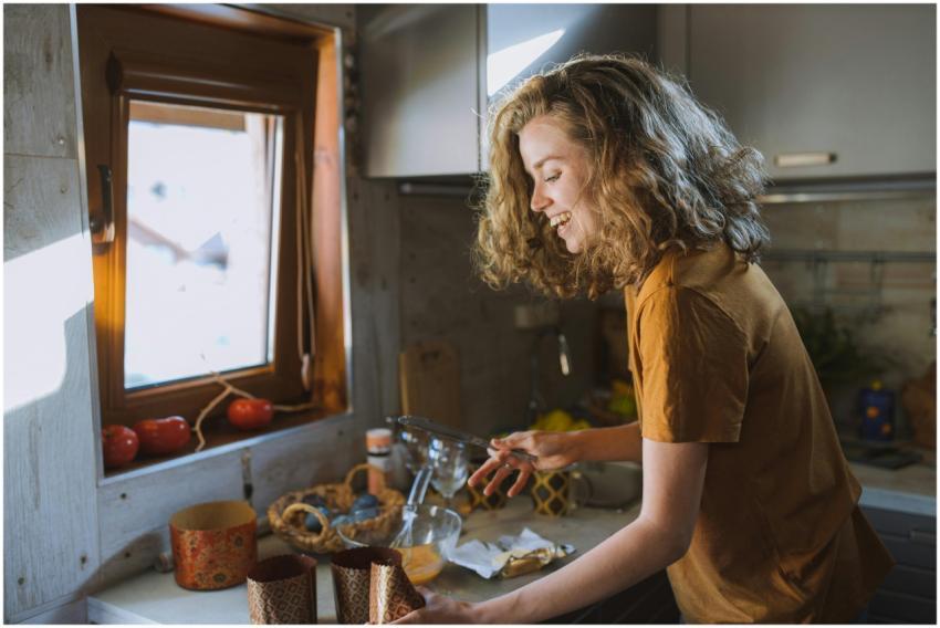 A happy woman with curly hair preparing food in a