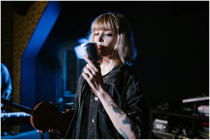 Young woman with tattoos, singing passionately int