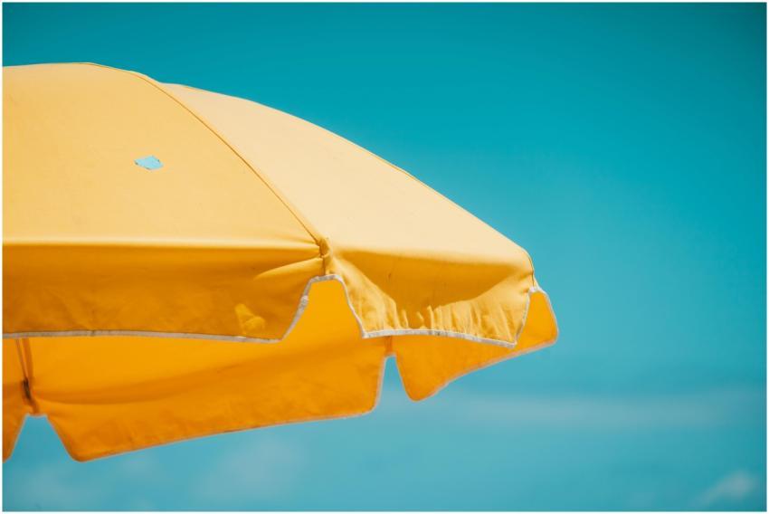 A vivid yellow beach umbrella set against a clear