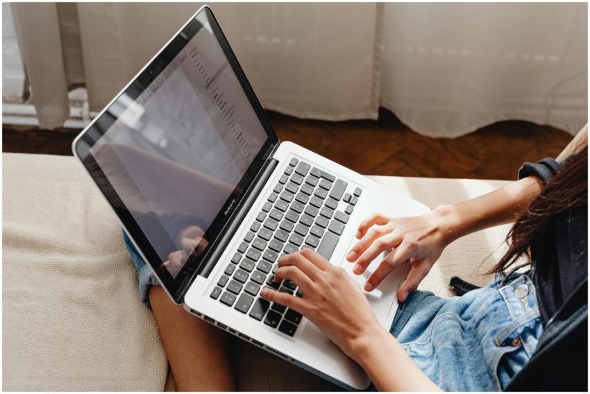 Close-up of a woman's hands typing on a laptop whi