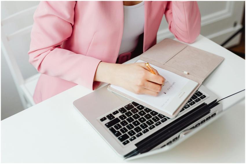Professional woman in pink blazer writing notes on