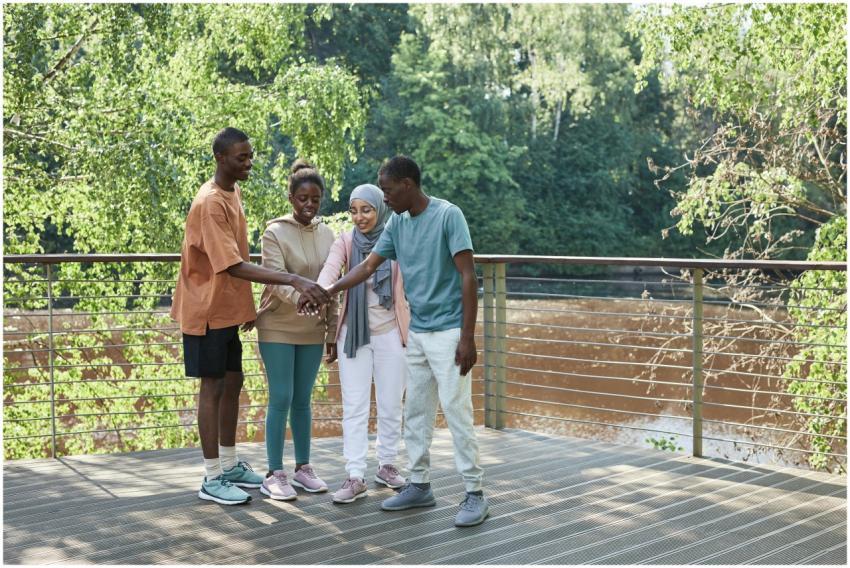 A diverse group of friends joining hands on a sunn