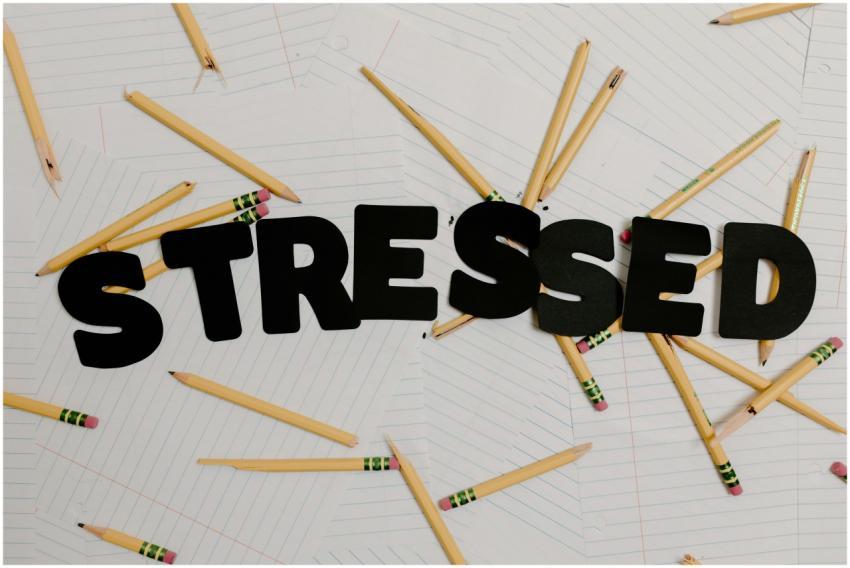 Stylized word 'stressed' with scattered pencils on