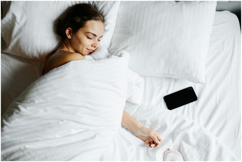 A young woman sleeps comfortably in bed with a sma