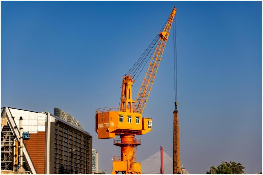 A vibrant orange construction crane stands tall ag