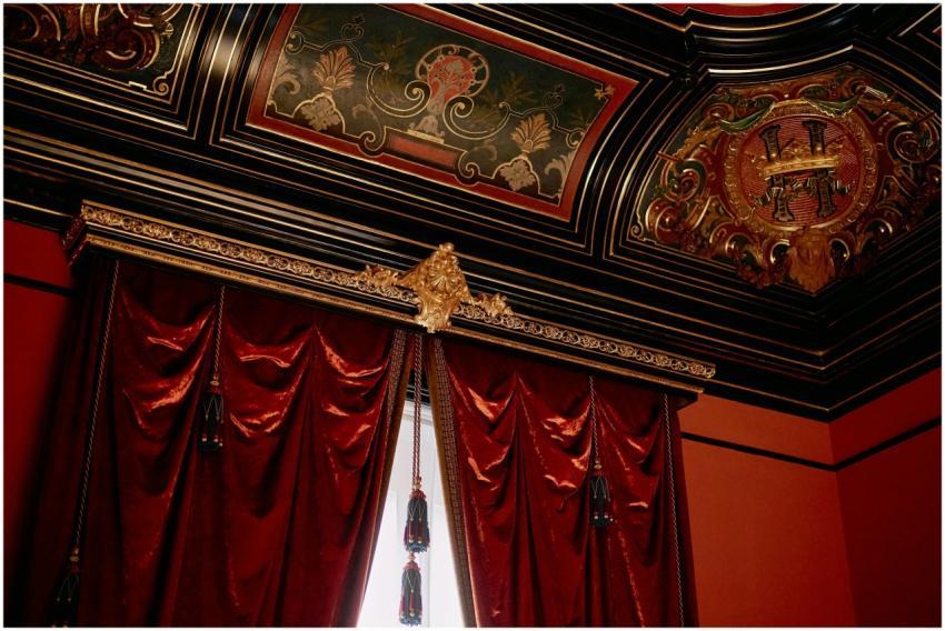 A luxurious room with ornate ceiling and rich red