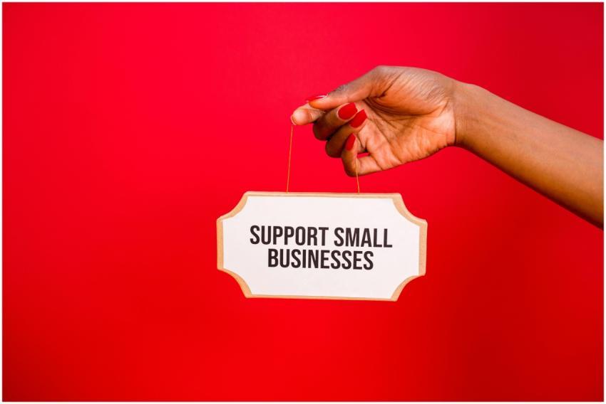 A hand holds a sign that reads 'Support Small Busi