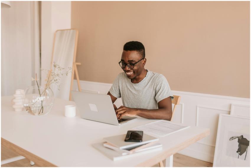 Happy young man typing on laptop in bright modern