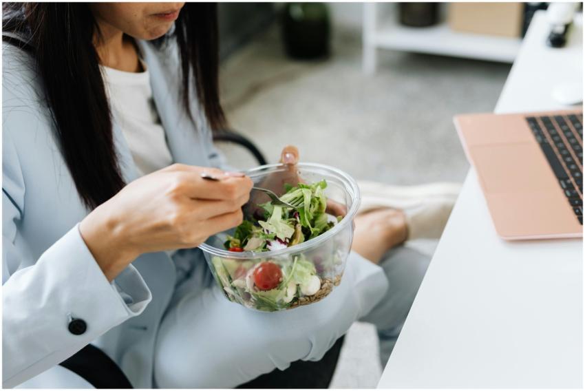 Adult woman eating a vegetable salad at her office