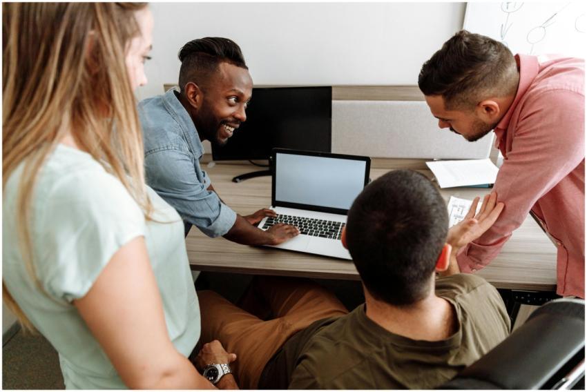 Four colleagues brainstorming around a laptop in a