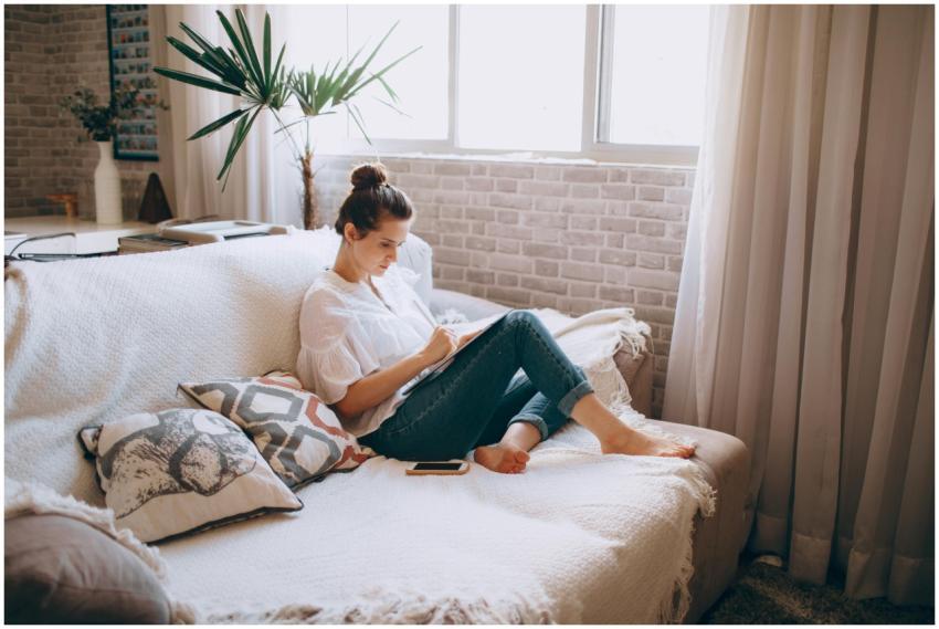 Adult woman sitting on sofa doing remote work on t