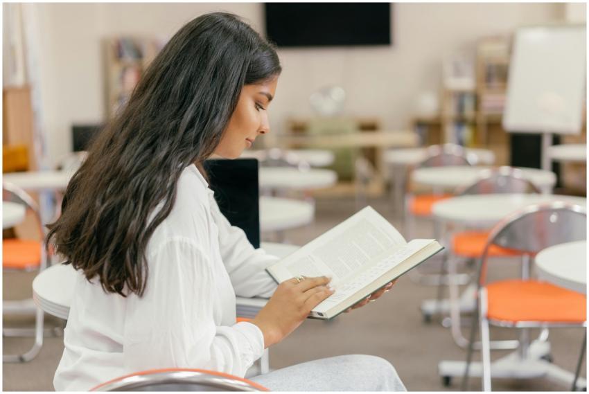 Young woman engrossed in reading a textbook in a m