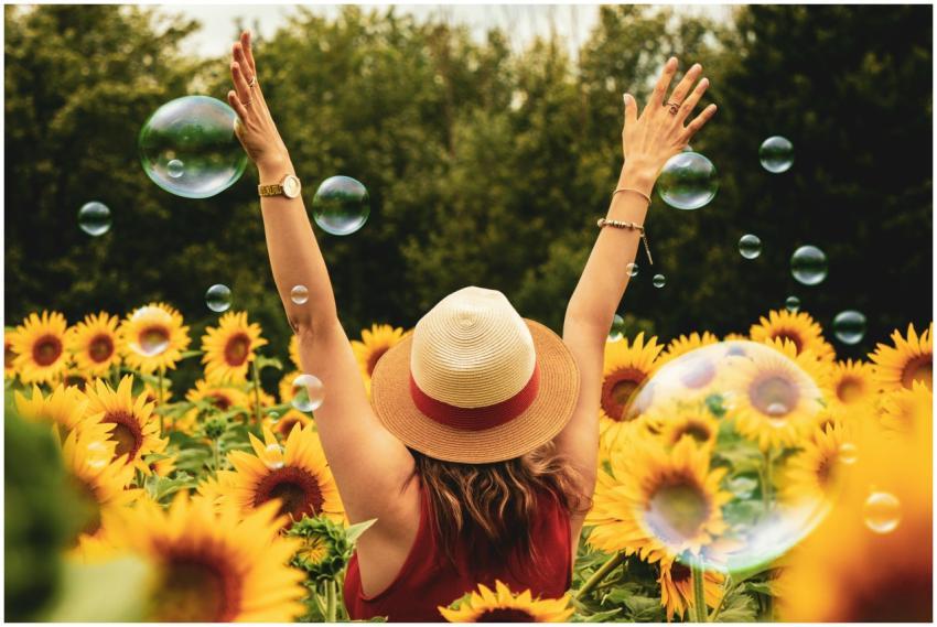 A joyful woman in a sunflower field with bubbles,
