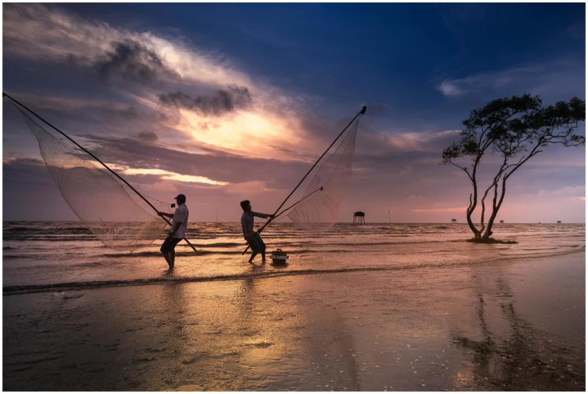 Two fishermen silhouetted against a vibrant sunset