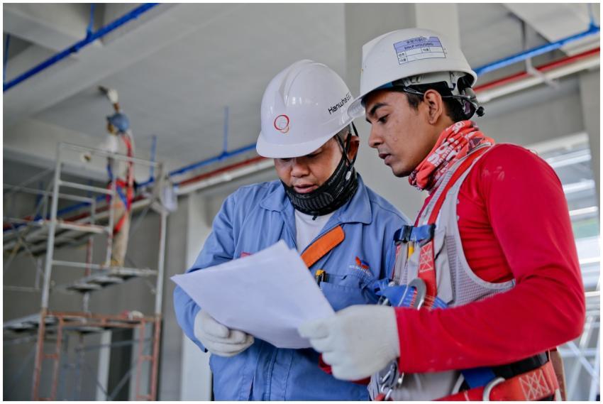 Two engineers in safety helmets reviewing construc
