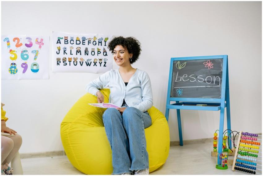 Smiling teacher sitting in a classroom, holding a