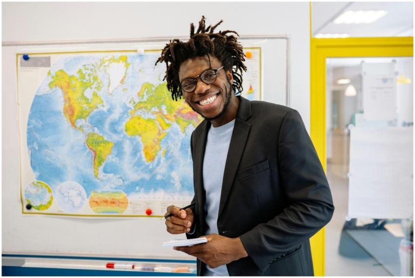 Energetic teacher smiling in front of a world map,