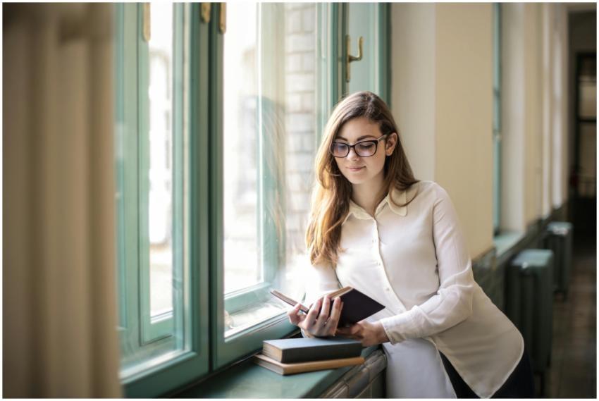 Woman in white long sleeves reading by the window