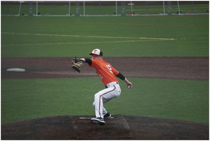 A baseball player pitching on a green field during
