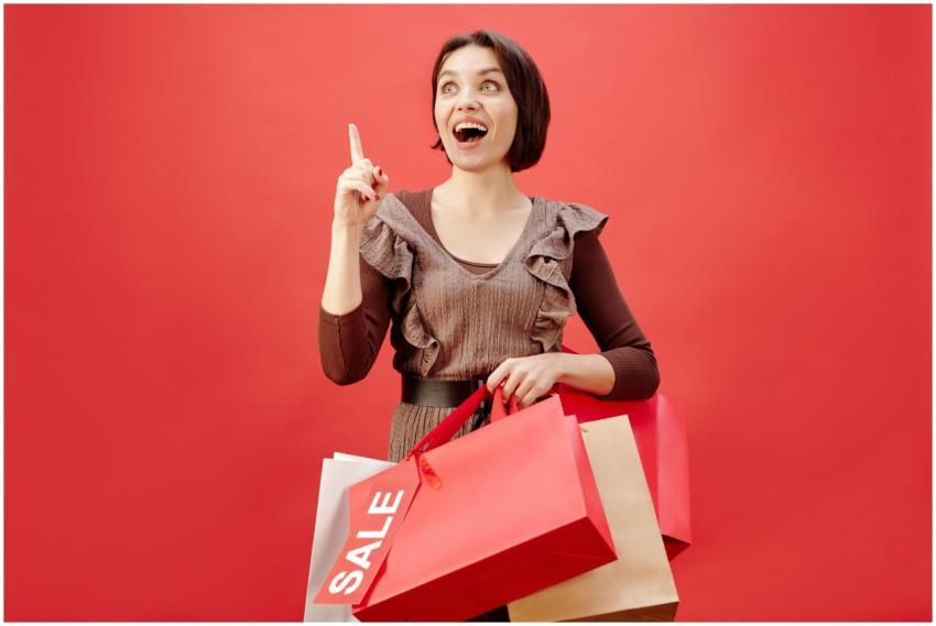 Cheerful woman with shopping bags celebrating a sa