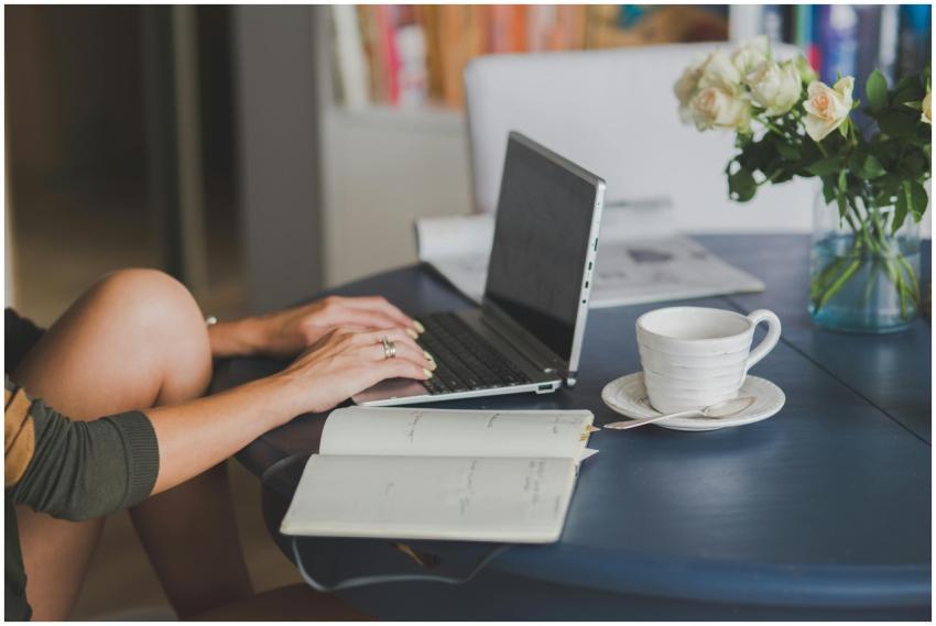 Female freelancer using laptop with coffee at home