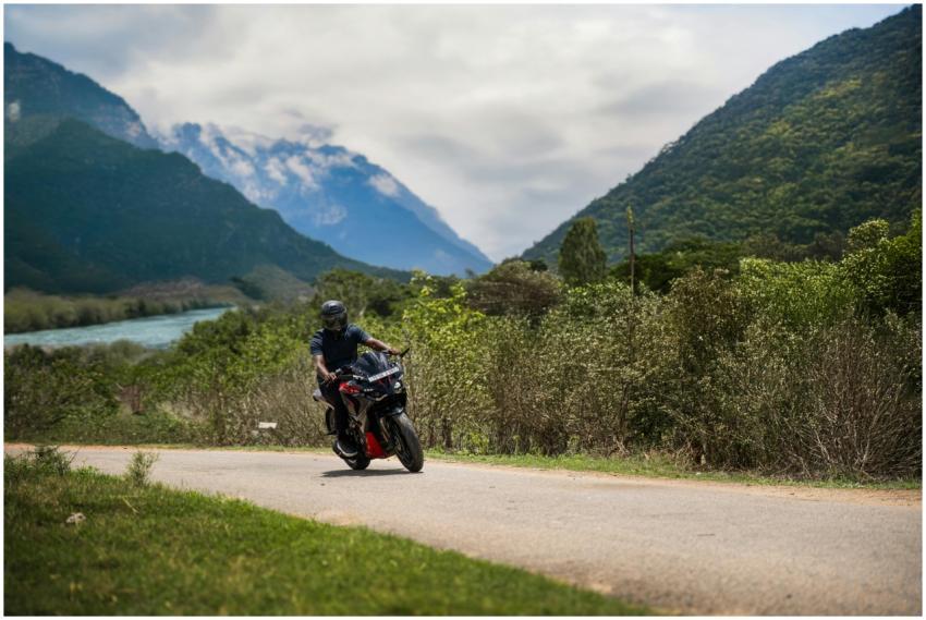 A motorcyclist navigates a winding road through lu