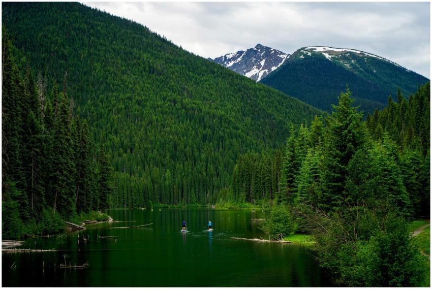 Two people paddleboarding on a serene lake in Mann