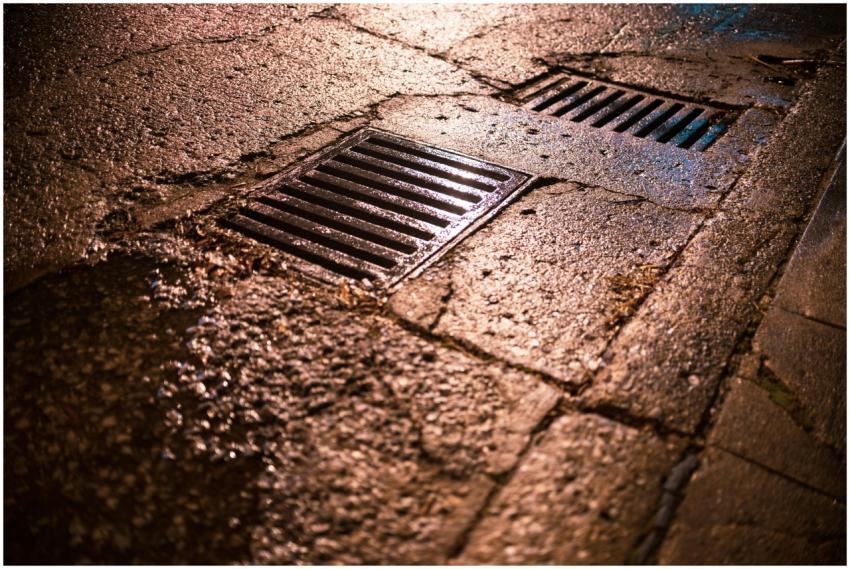 Nighttime shot of wet asphalt road with drainage g