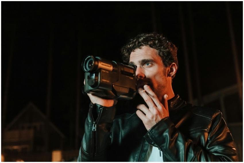 A man in a leather jacket smoking a cigarette whil