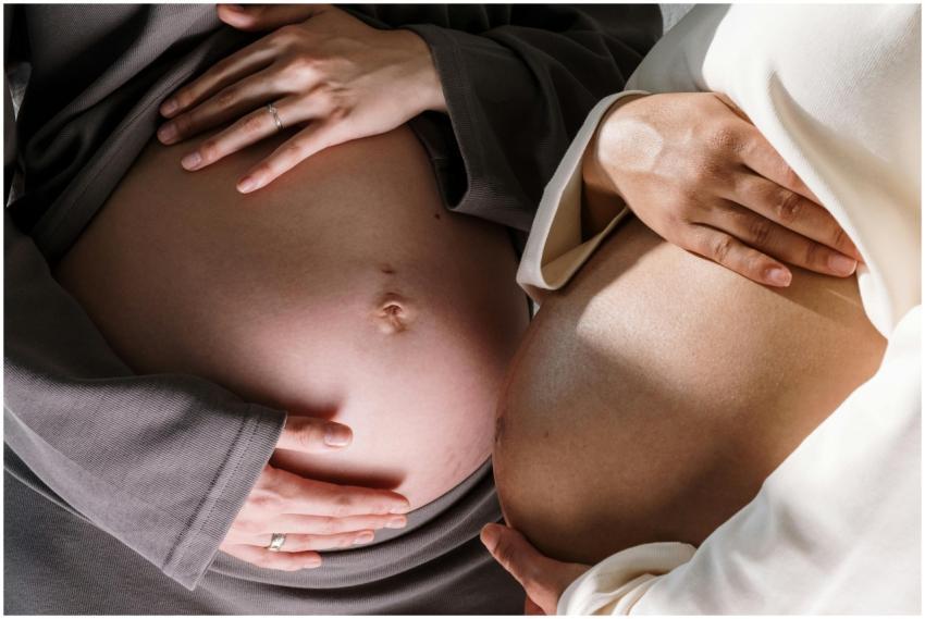 Two pregnant women gently touching their bellies,